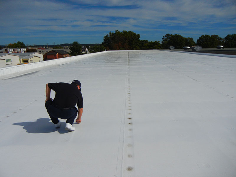 man on a low slope roofing