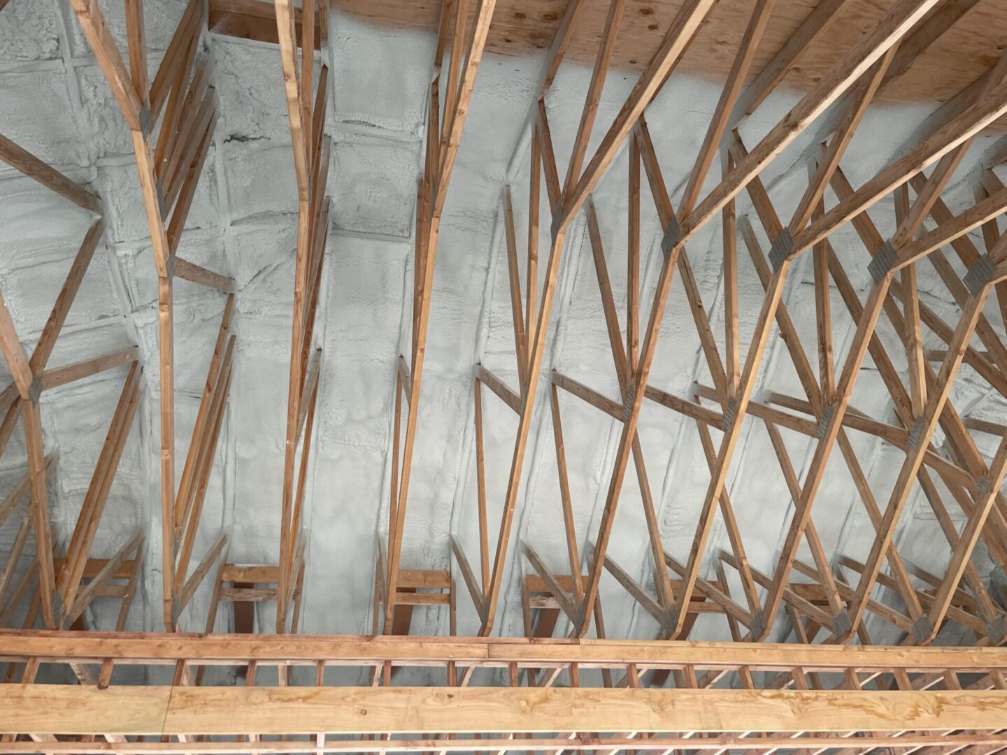 ongoing construction with wooden beams and spray on insulation on ceiling